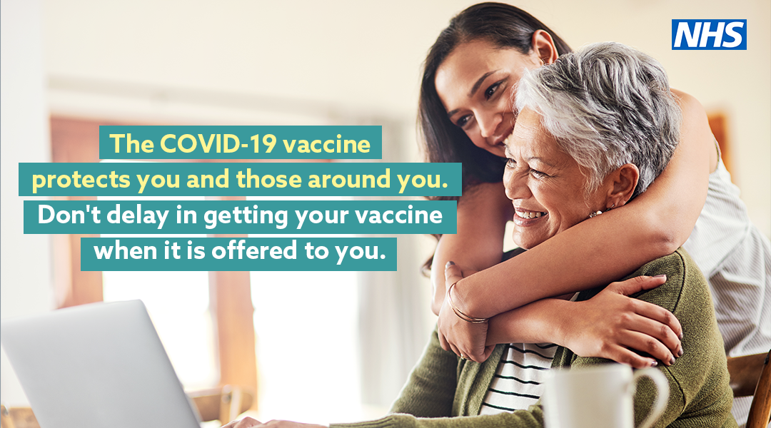 Two women hugging. Text reads: The Covid-19 vaccine protects you and those around you. Don't delay in getting your vaccine when it's offered to you.